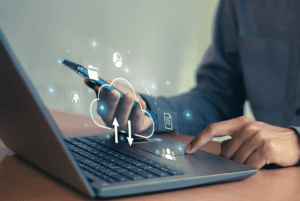 Person nutzt Smartphone und Laptop für Cloud- und IT-Sicherheitslösungen.